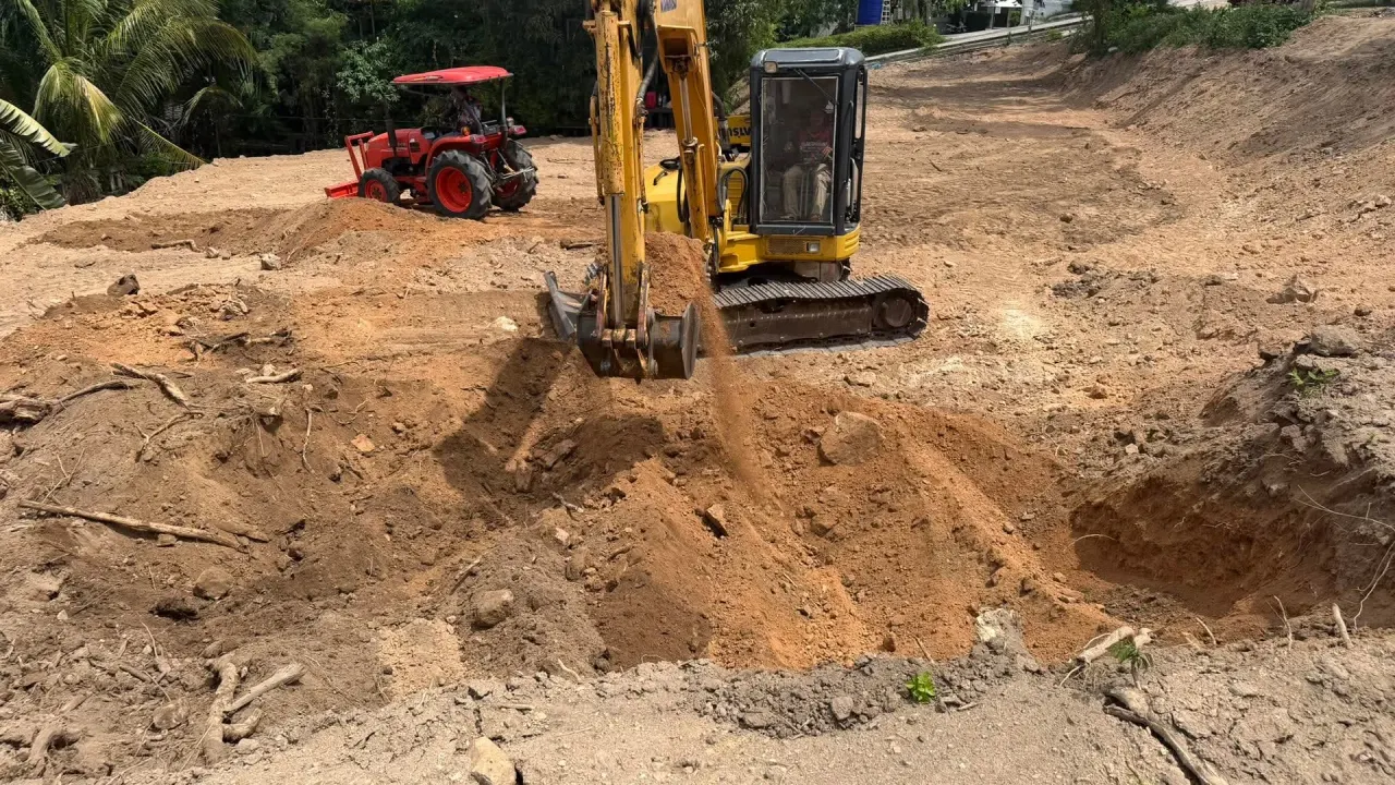 Excavator digging while the tractor spreads soil across the site