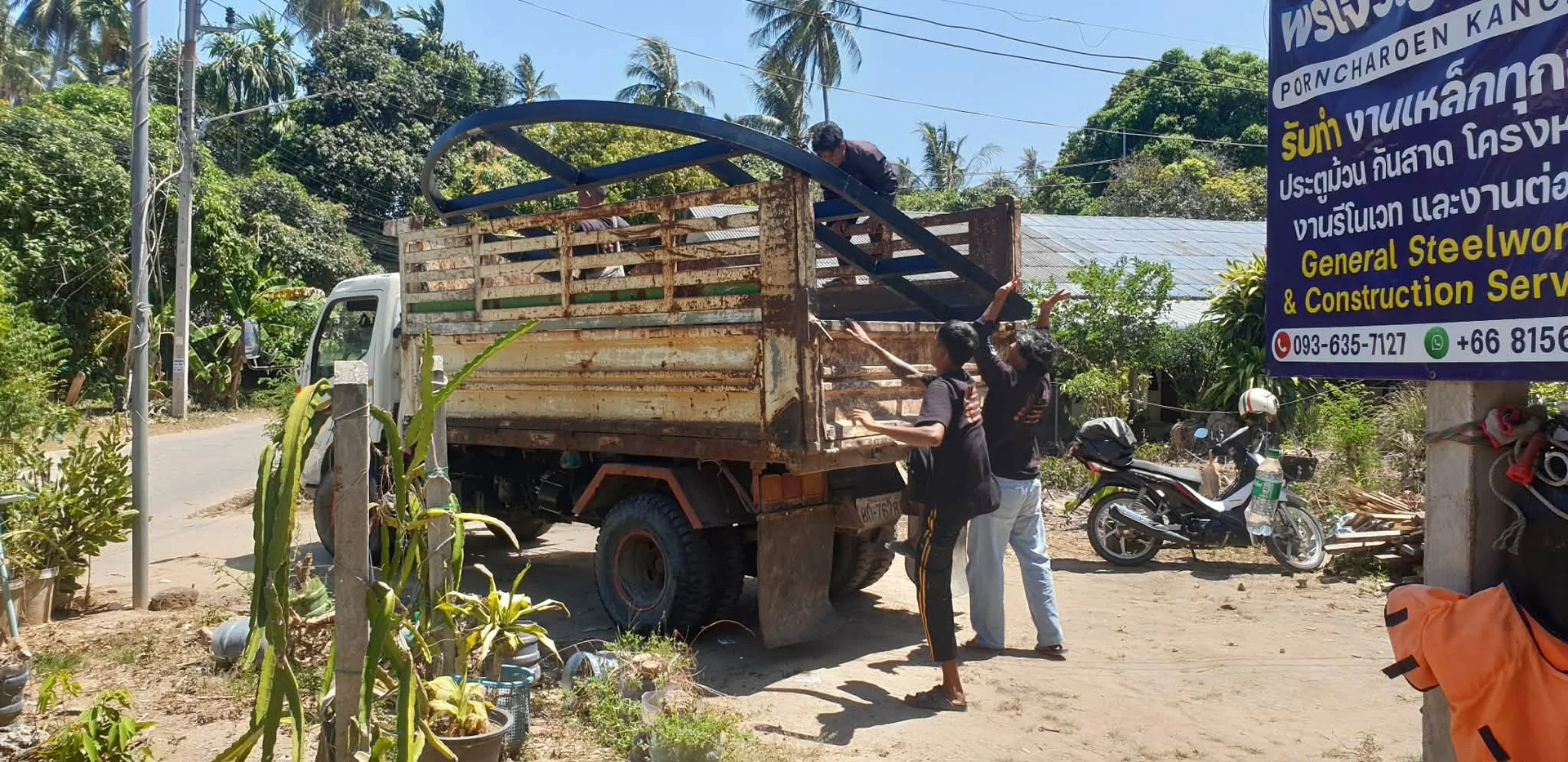 Loading semicircular steel arch for entrance door onto Hino 300 truck