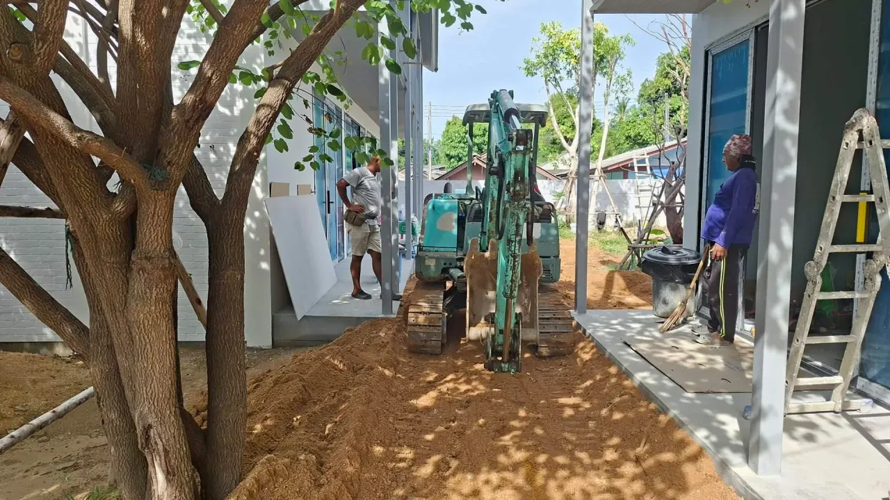 Compact excavator working in the tight space between finished villas