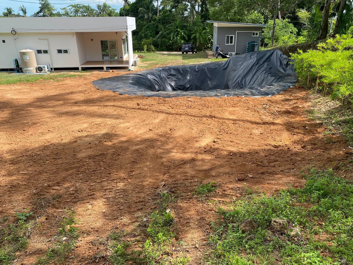 Completed pool pit with liner, surrounded by cleared and leveled ground