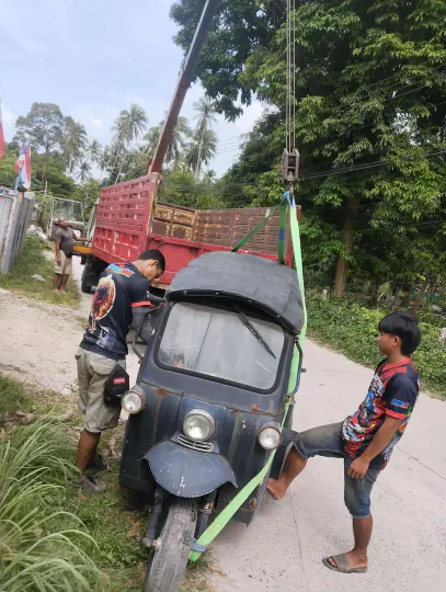 Using a crane to load a tuk tuk onto a truck for safe transport